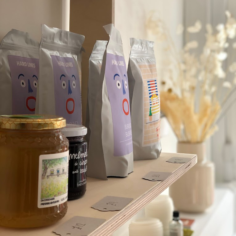 Raw honey and coffee with quirky, colourful packagin sit on a sun-lit shelf. A photo taken inside of the Lola cafe.